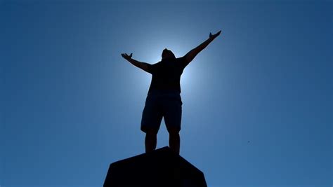 man holding his hand up on cliff